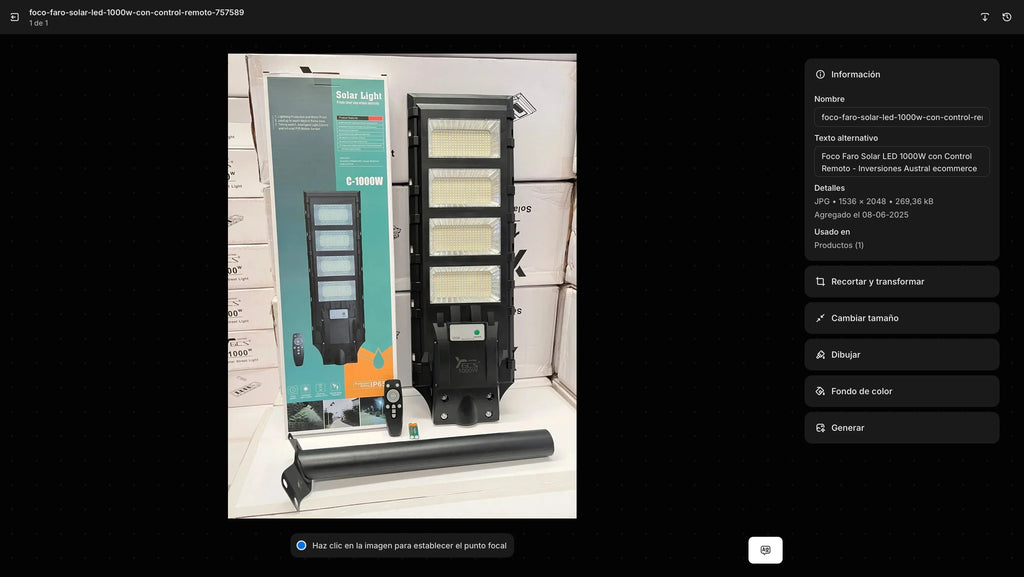 El Foco Solar LED 1400W Exterior con Sensor de Movimiento - Luz Blanca Fría se muestra erguido junto a su caja, control remoto y varilla de montaje sobre una superficie blanca, con cajas apiladas al fondo.